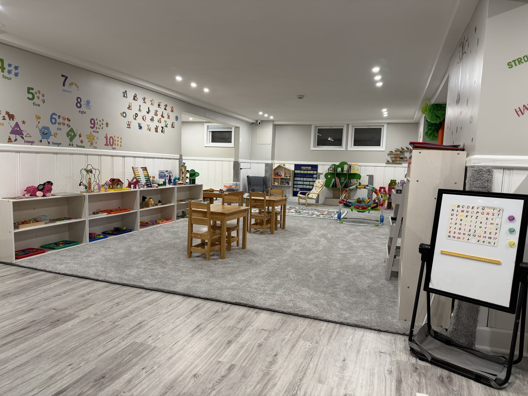 The actual Bluebird Learning Nest main activity room with child-sized tables, organized learning materials, and open space for play